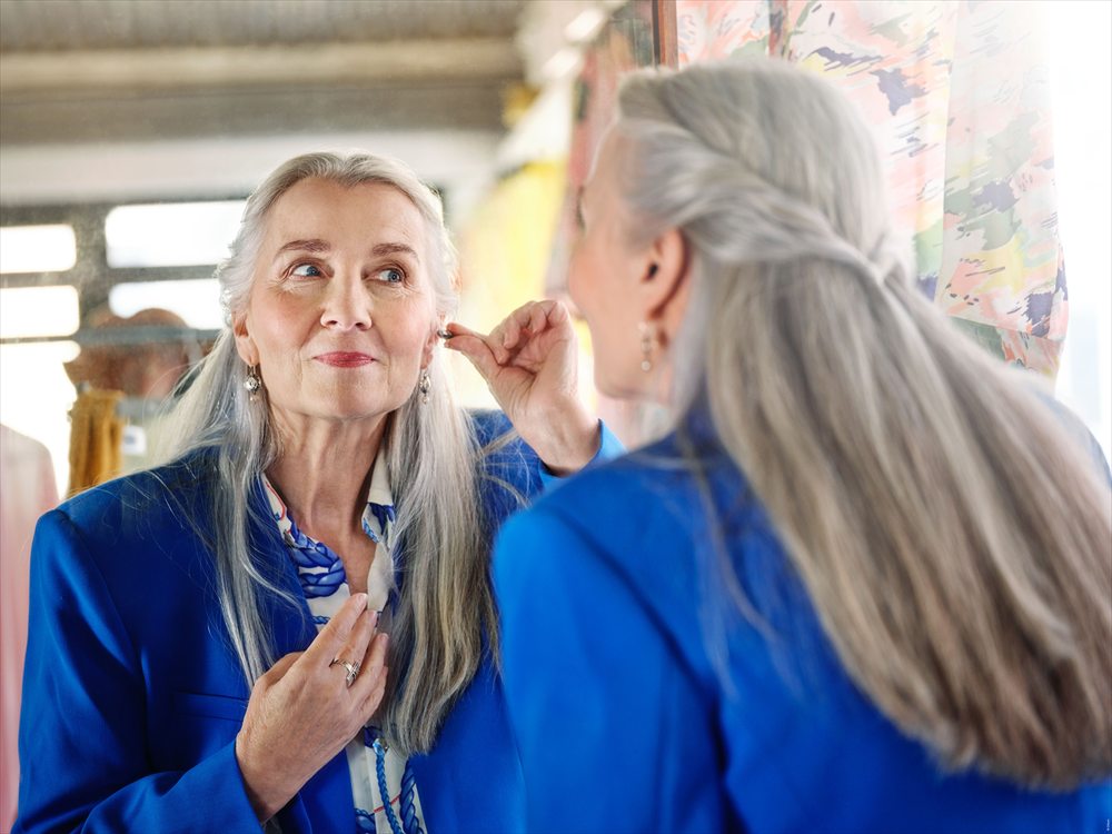 Personne sereine plaçant son aide auditive devant un miroir