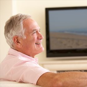 Homme senior regardant la télévision, télécommande en main